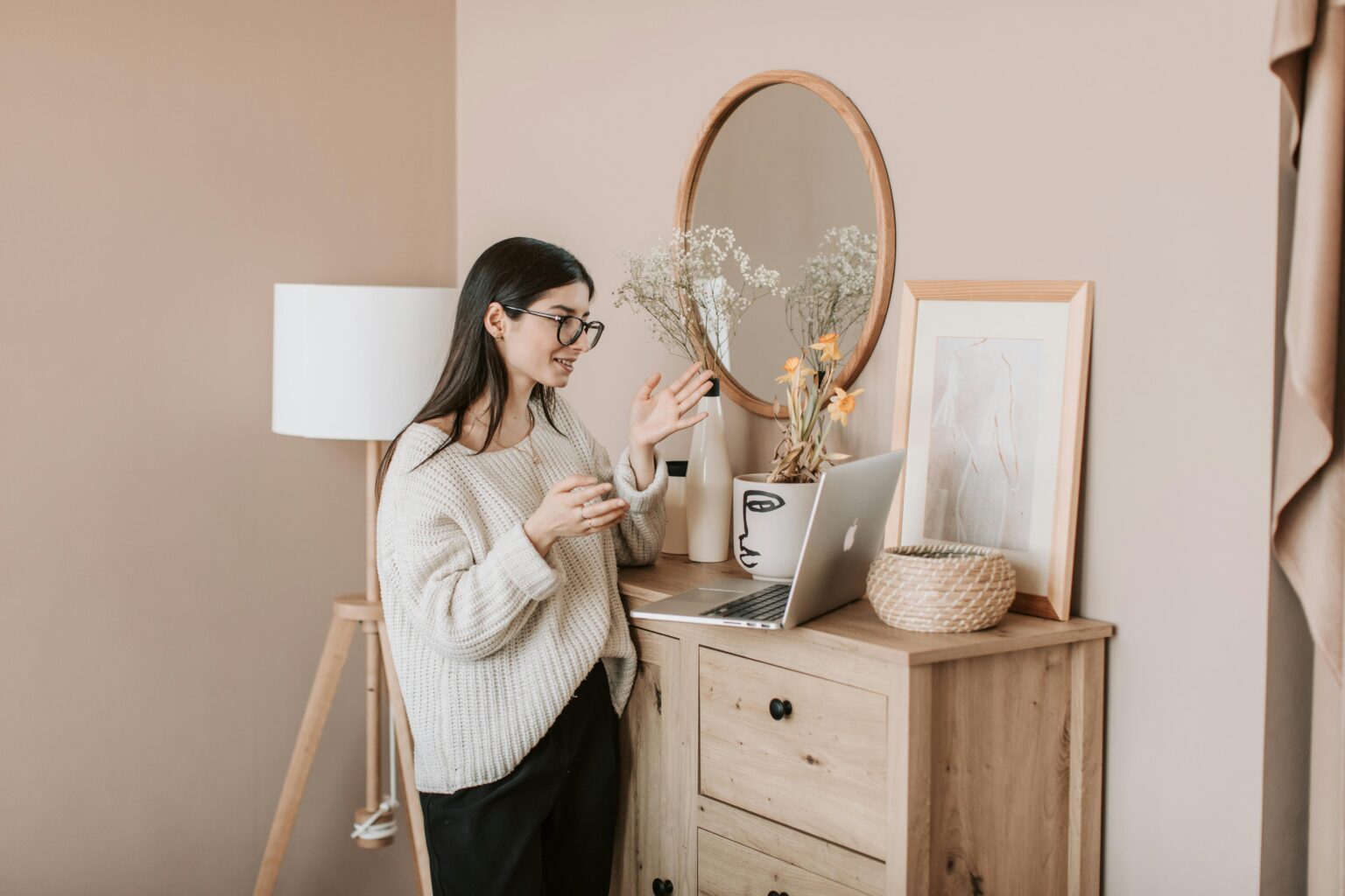 Young woman engaging in a video call from a cozy, modern living room with a laptop.