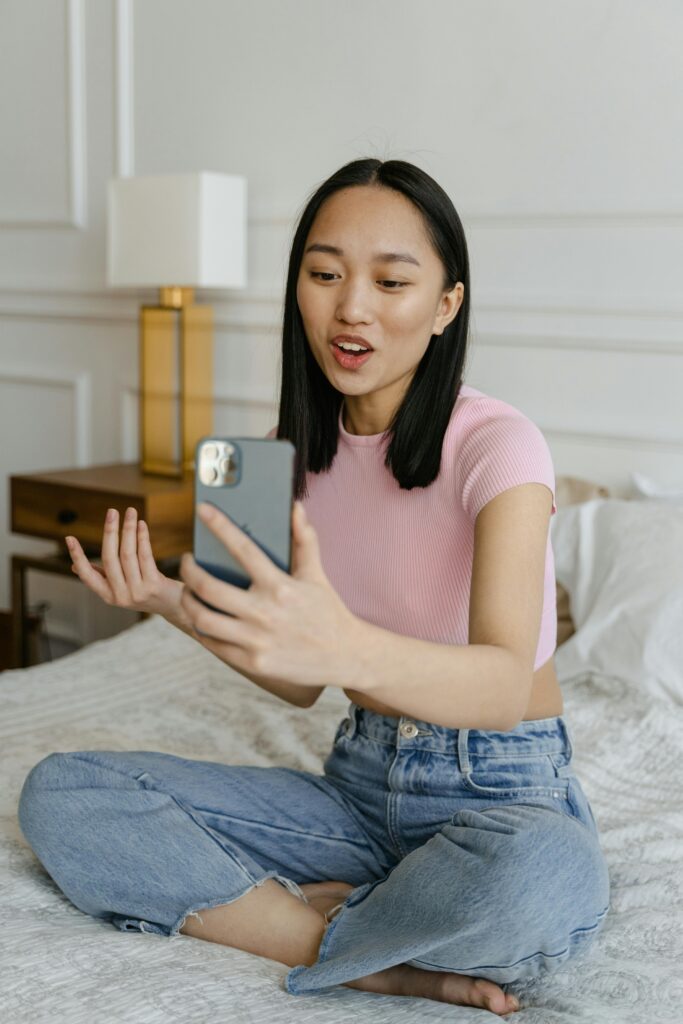 Woman in pink crop top using smartphone for a video call indoors.